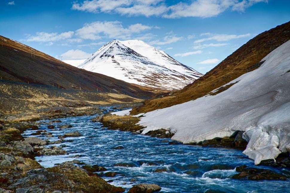 Free Image of Stream Flowing Through Valley With Snow Covered Mountain 
