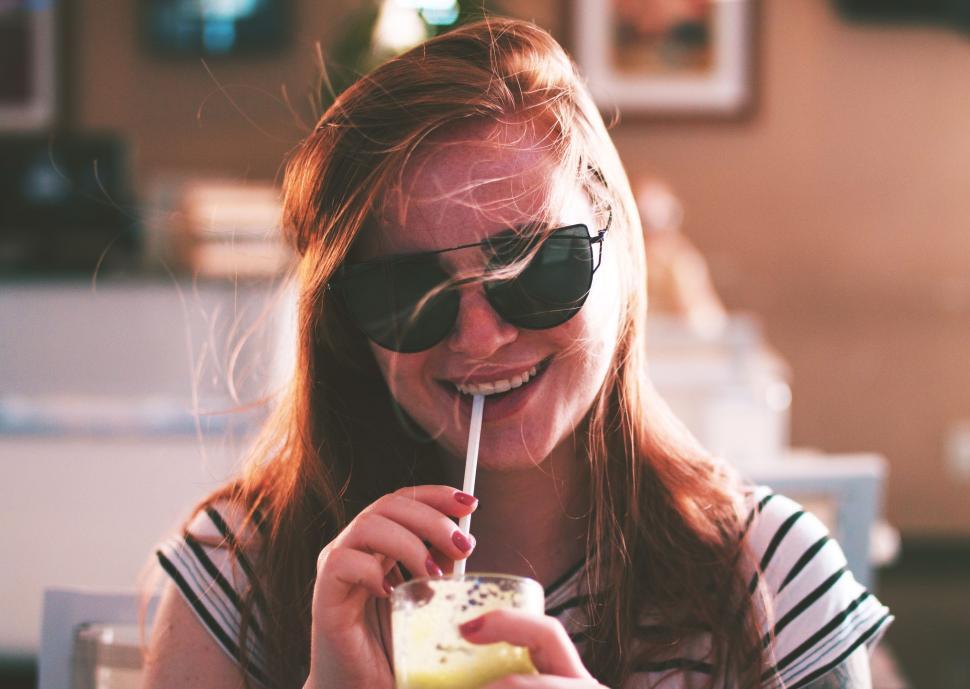 Free Image of Woman Wearing Sunglasses Drinking a Drink 