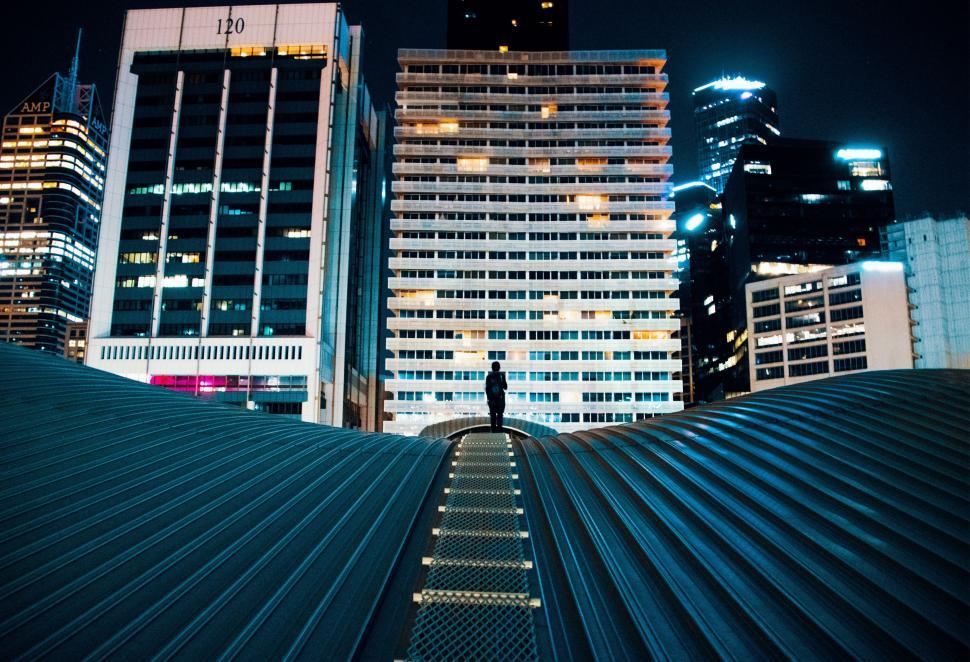 Free Image of Person Standing on Walkway in Front of Tall Buildings 