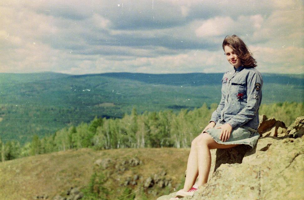 Free Image of Woman Sitting on Top of Rock Next to Forest 