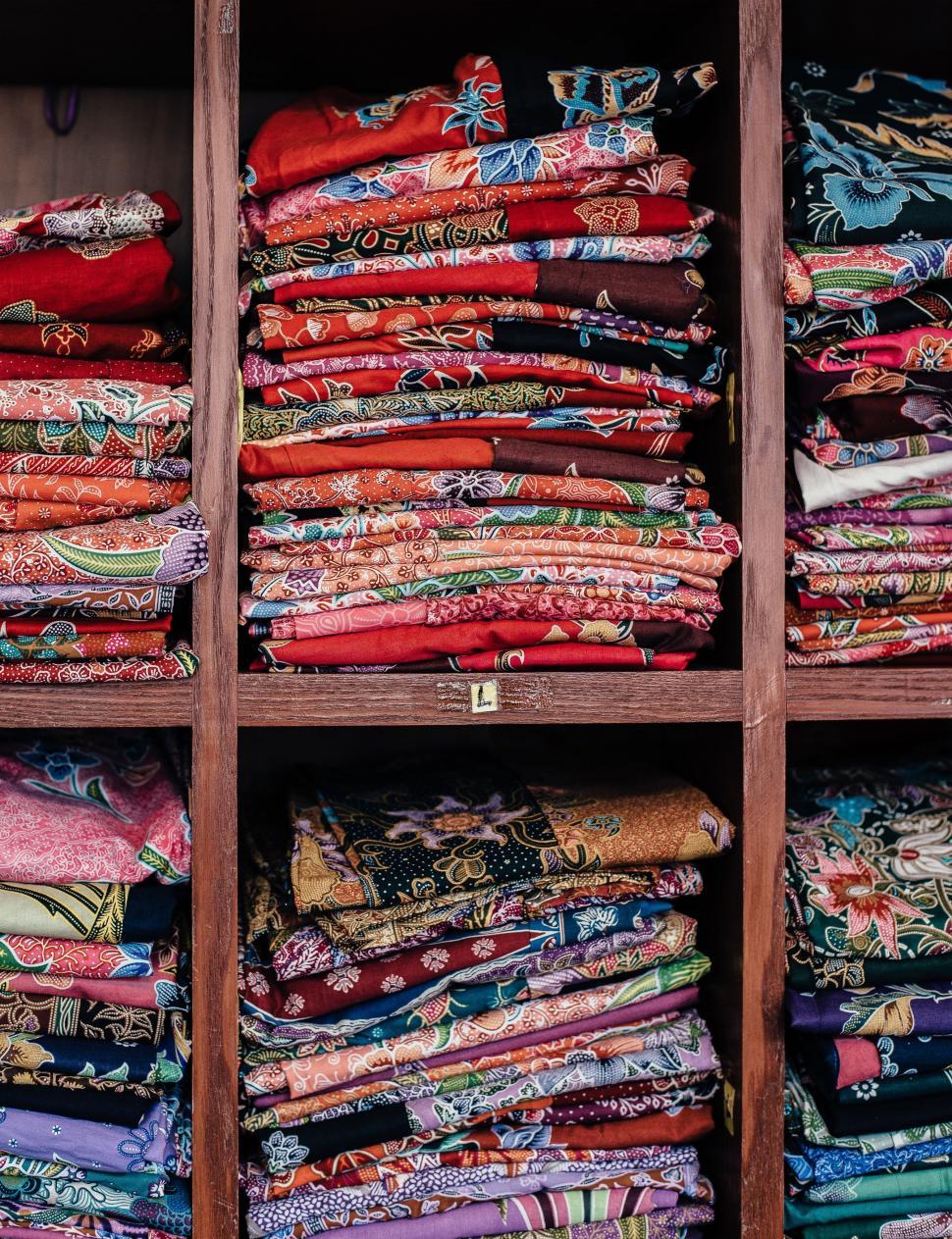 Free Image of Colorful Fabrics Arranged on Wooden Shelf 