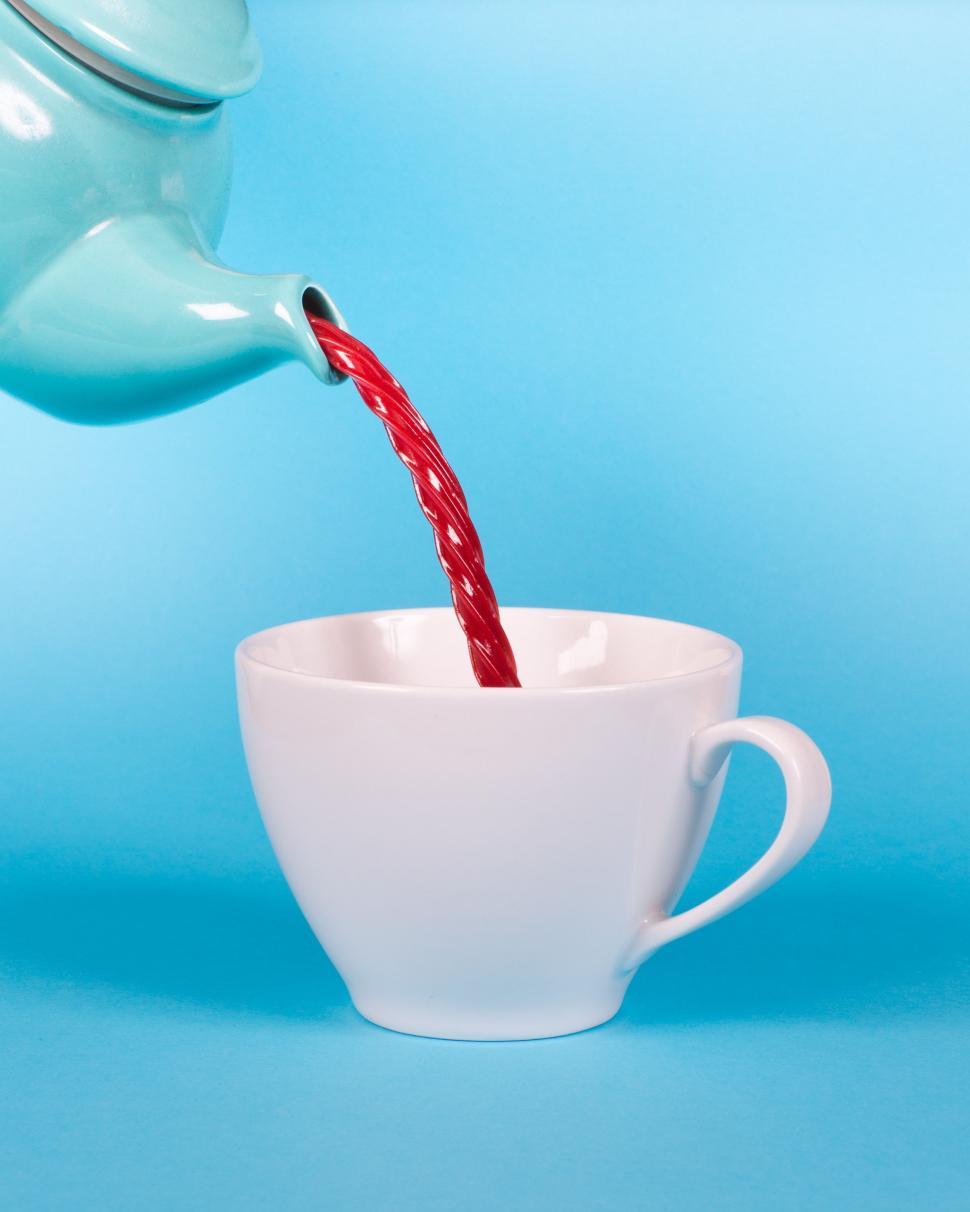 Free Image of Teapot Pouring Red Liquid Into White Cup 