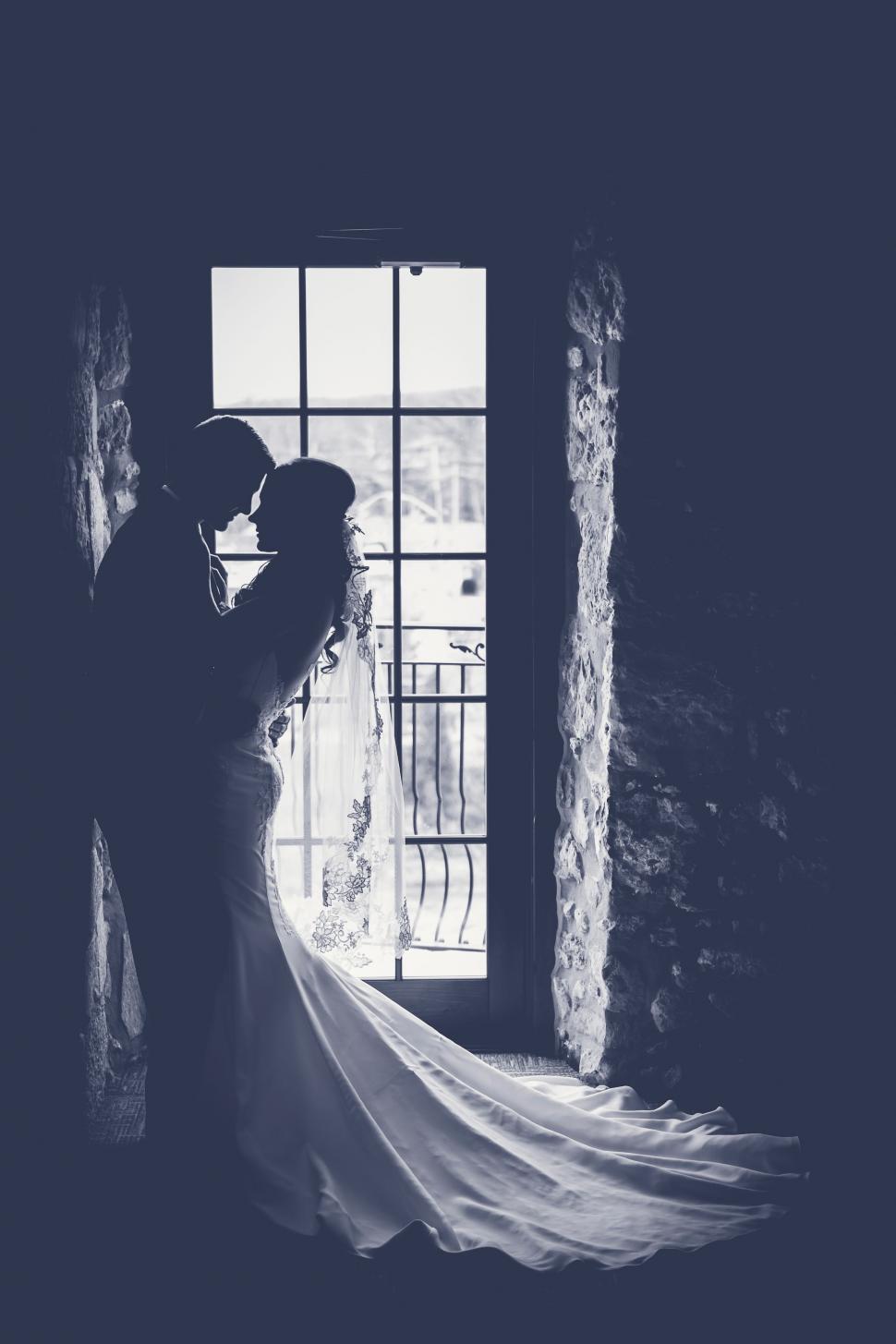 Free Image of Bride and Groom Standing in Front of Window 