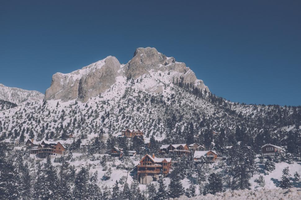 Free Image of Snow Covered Mountain With Houses in the Foreground 
