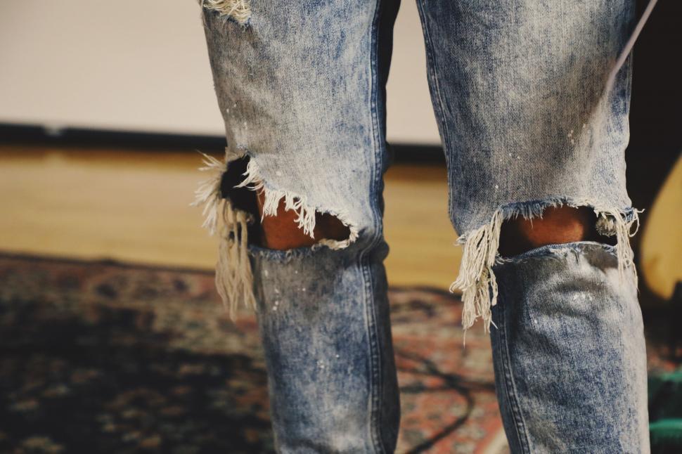 Free Image of Ripped Jeans With Guitar in Background 