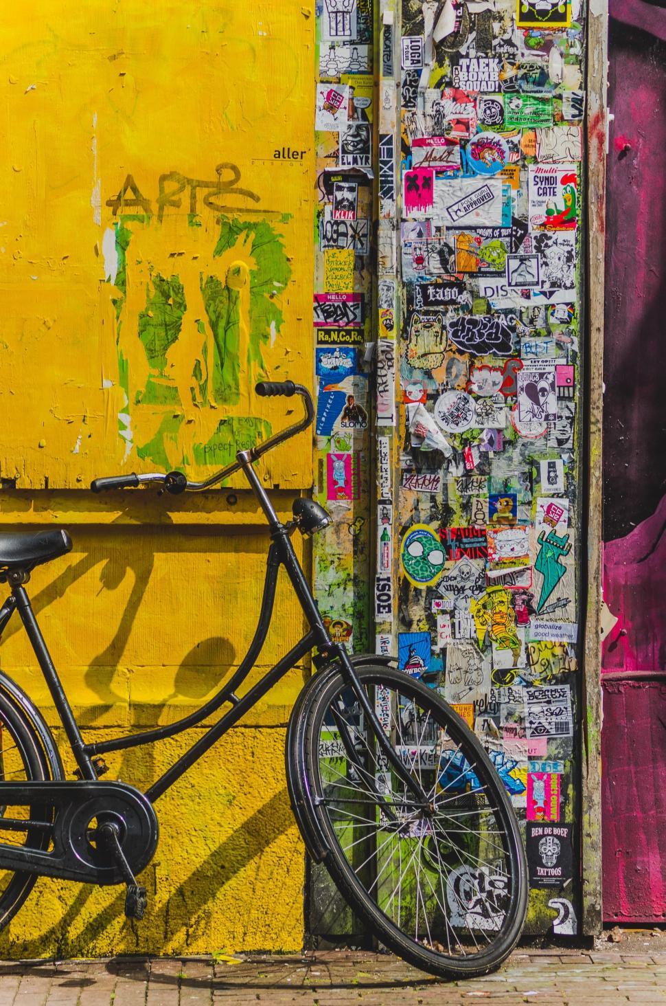 Free Image of Bicycle Parked Next to Sticker-Covered Wall 
