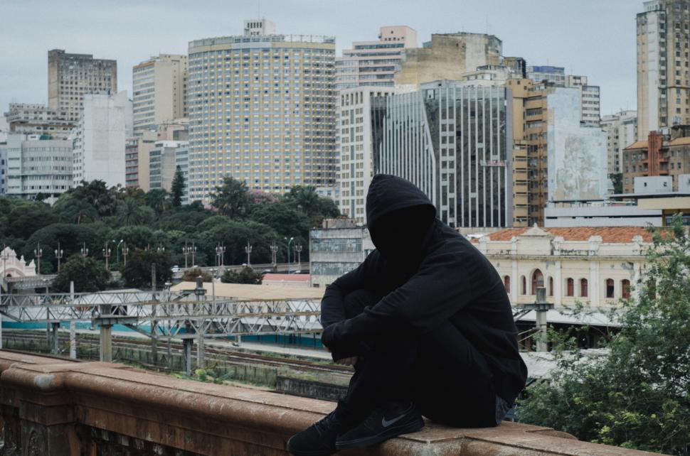 Free Image of Person Sitting on Ledge With City in Background 