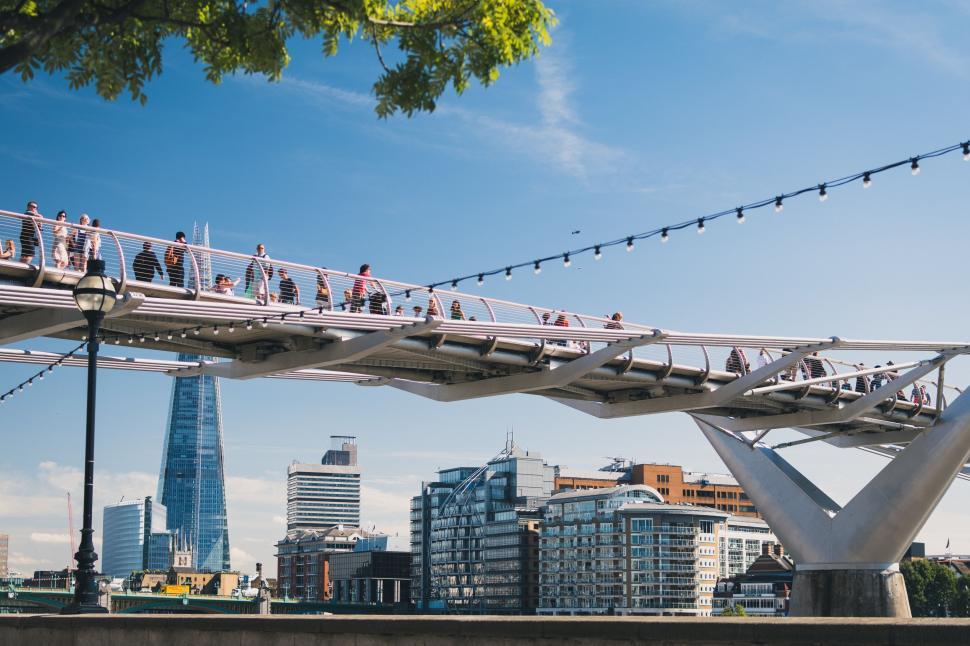 Free Image of Group of People Walking Across Bridge Over River 