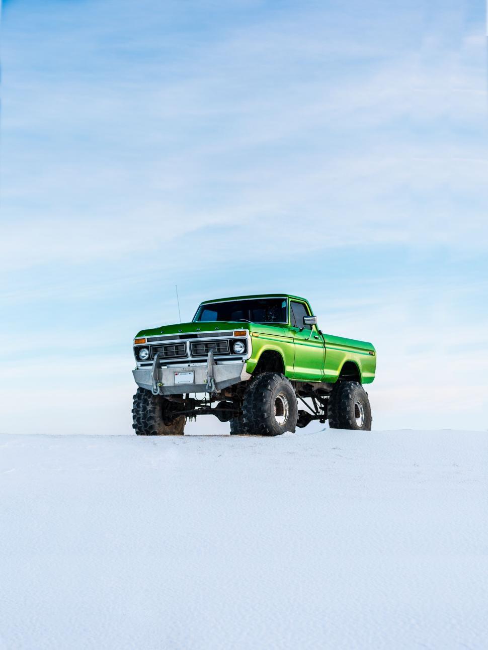Free Image of Green Truck Driving Across Snow Covered Field 