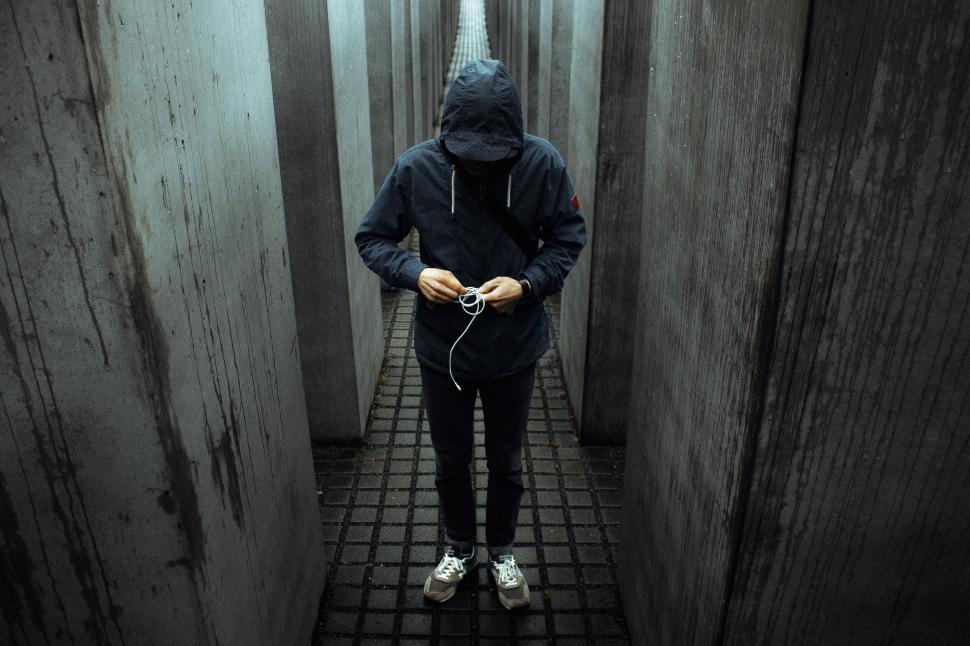 Free Image of Man in Hooded Jacket Walking Down Narrow Hallway 