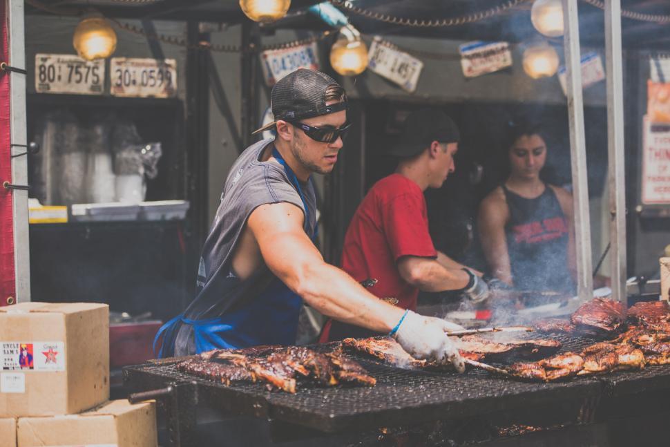 Free Image of Man Grilling Meat in Front of Group of People 