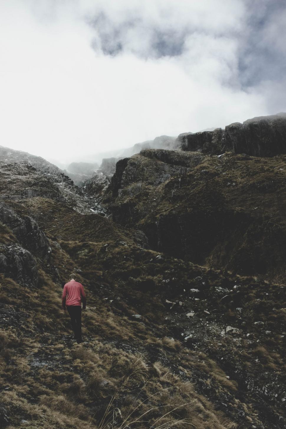Free Image of Man Walking Up Hill on Cloudy Day 