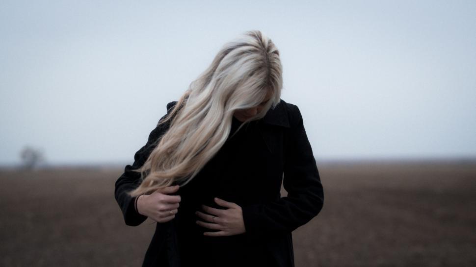 Free Image of Woman Standing in Field With Wind-Blown Hair 