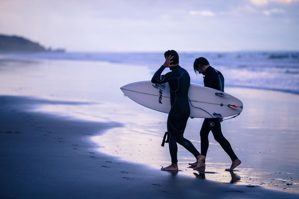 Free Image of Two Surfers Walking on the Beach With Surfboards 