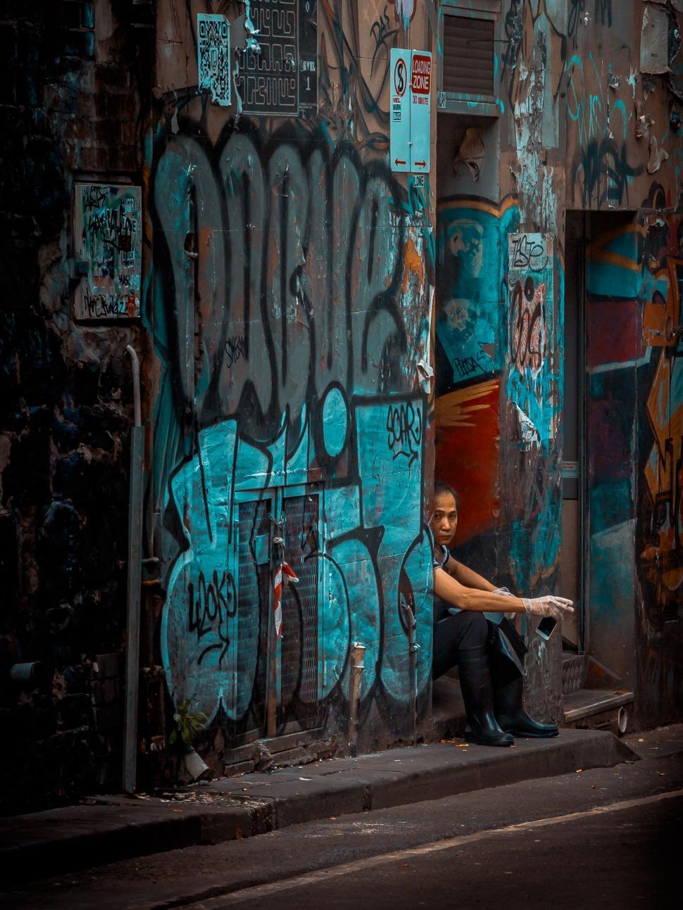 Free Image of Man Sitting on Side of Graffiti-Covered Building 