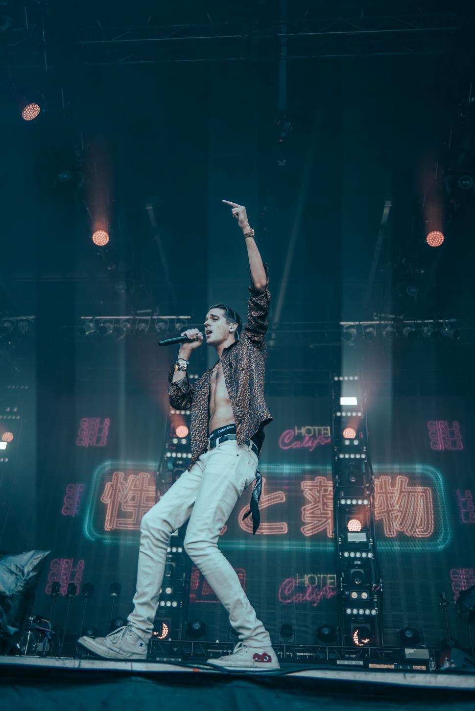 Free Image of Man Standing on Top of Stage Holding Microphone 