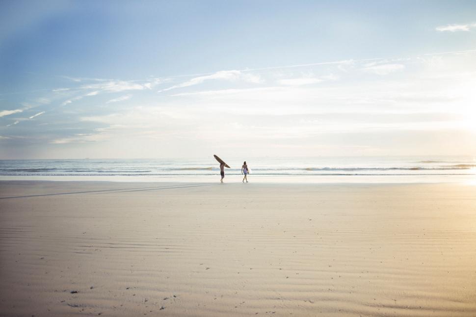 Free Image of Couple Walking Across Sandy Beach 