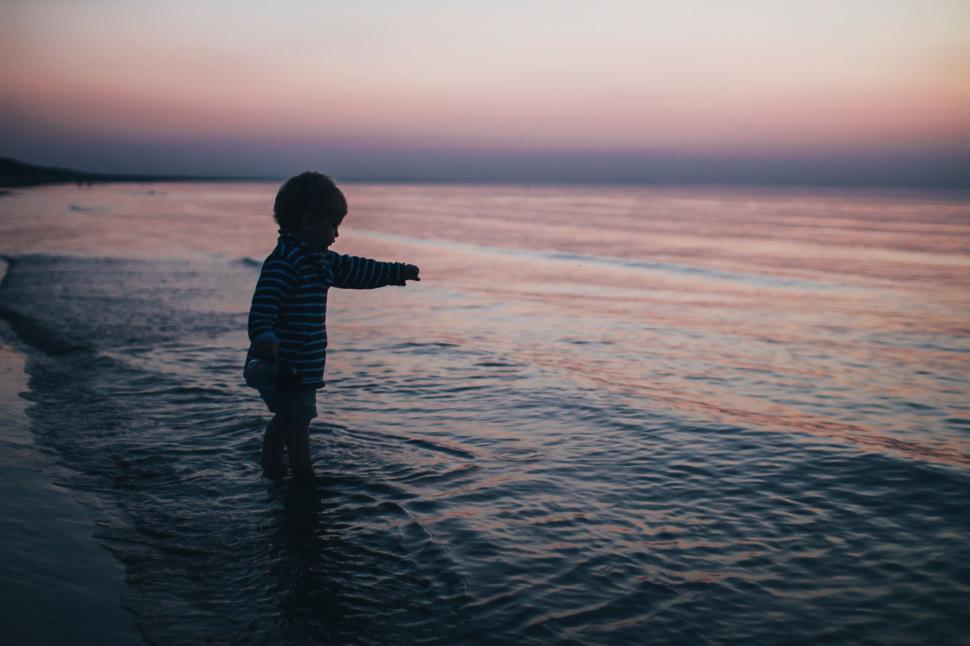 Free Image of Little Boy Standing on Beach Next to Ocean 