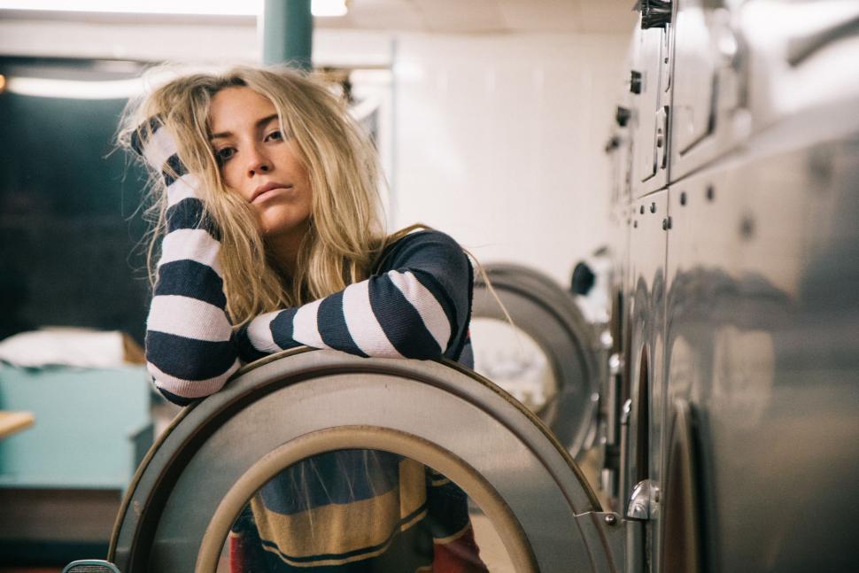 Free Image of Woman Sitting on Dryer Next to Dryer 