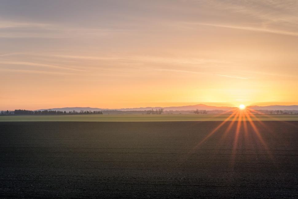 Free Image of The Sun Sets Over a Vast Field 