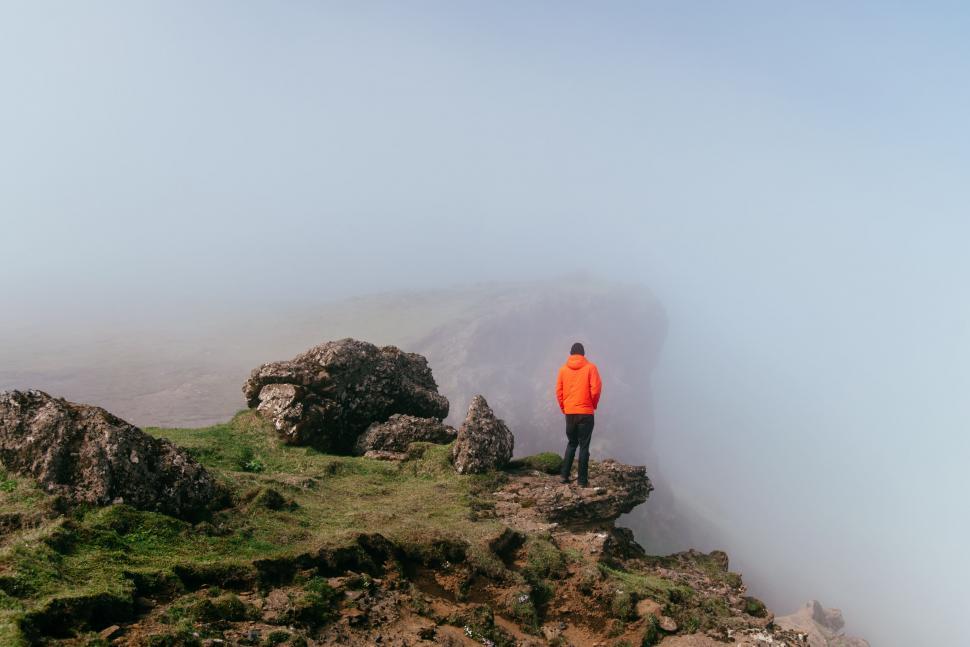 Free Image of Man in Orange Jacket Standing on Top of Mountain 