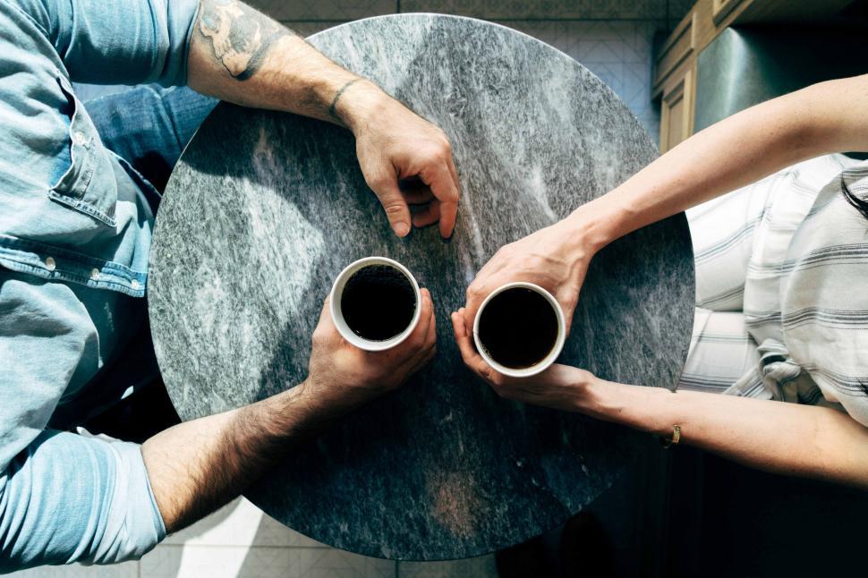 Free Image of Two People Sitting at a Table Holding Coffee Cups 