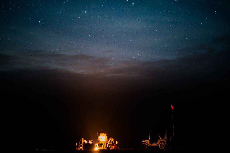 Free Image of Group of People Sitting Around Campfire Under Night Sky 