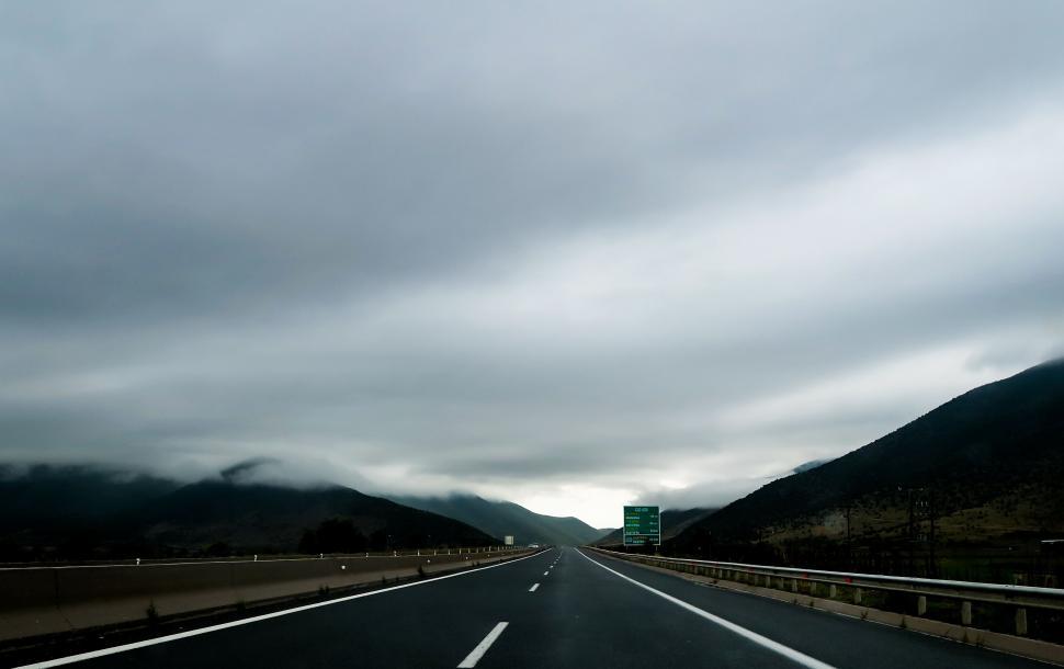 Free Image of Car Driving Down Highway Under Cloudy Sky 