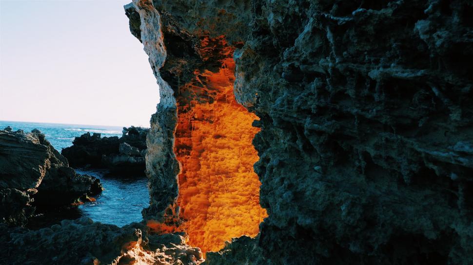 Free Image of Orange Substance Growing From Crack in Rock 