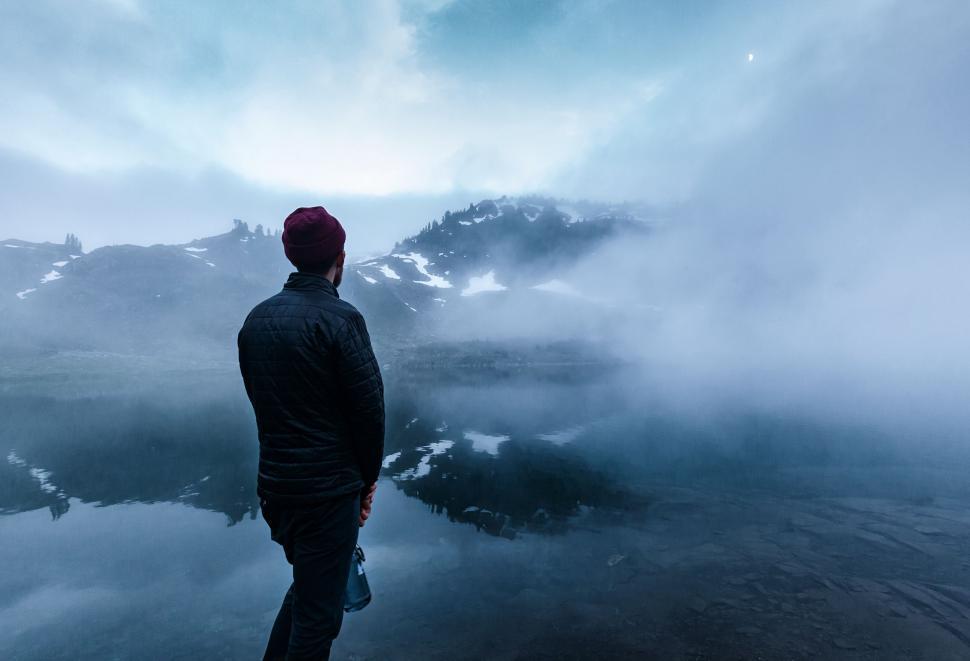 Free Image of Man Standing on Mountain Peak by Water 