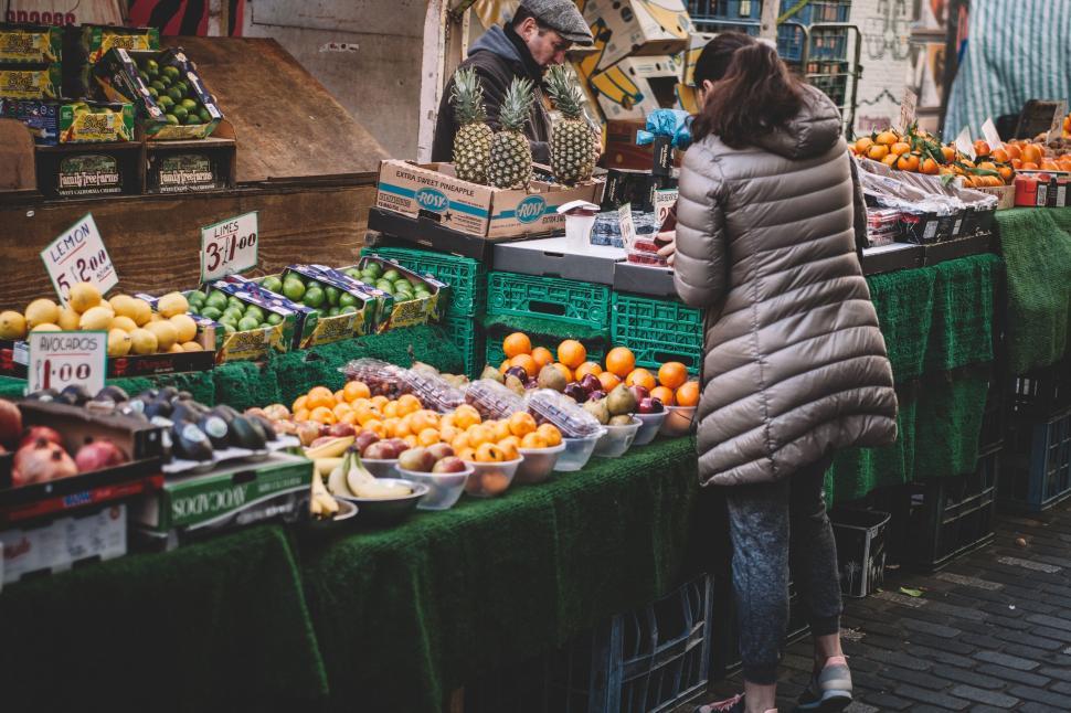 Free Image of Woman Standing in Front of Fruit Stand 