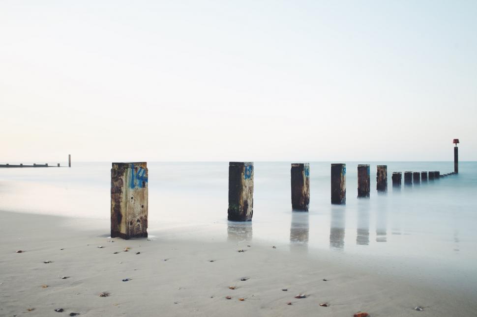 Free Image of Beach With Multiple Poles Sticking Out of Water 