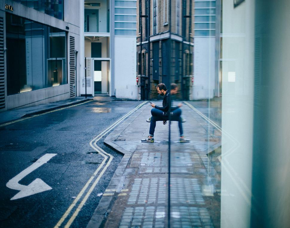 Free Image of Man Skateboarding Down City Street Next to Tall Buildings 