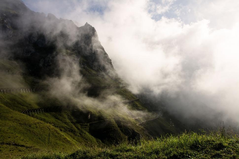 Free Image of Fog and Clouds Blanketing Lush Green Hillside 