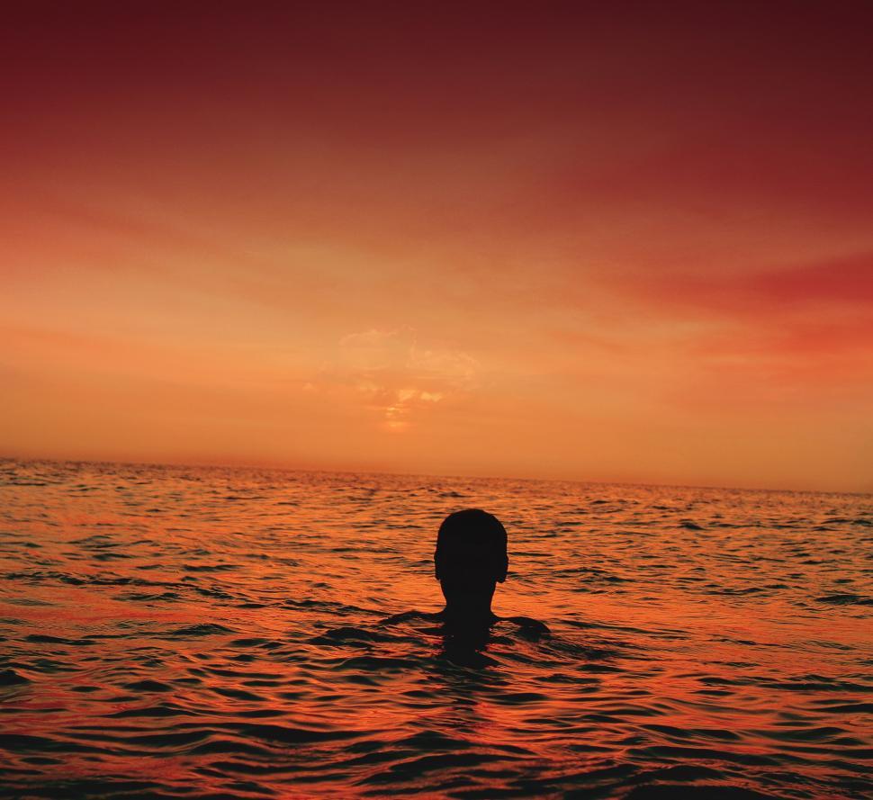 Free Image of Person Swimming in the Ocean at Sunset 