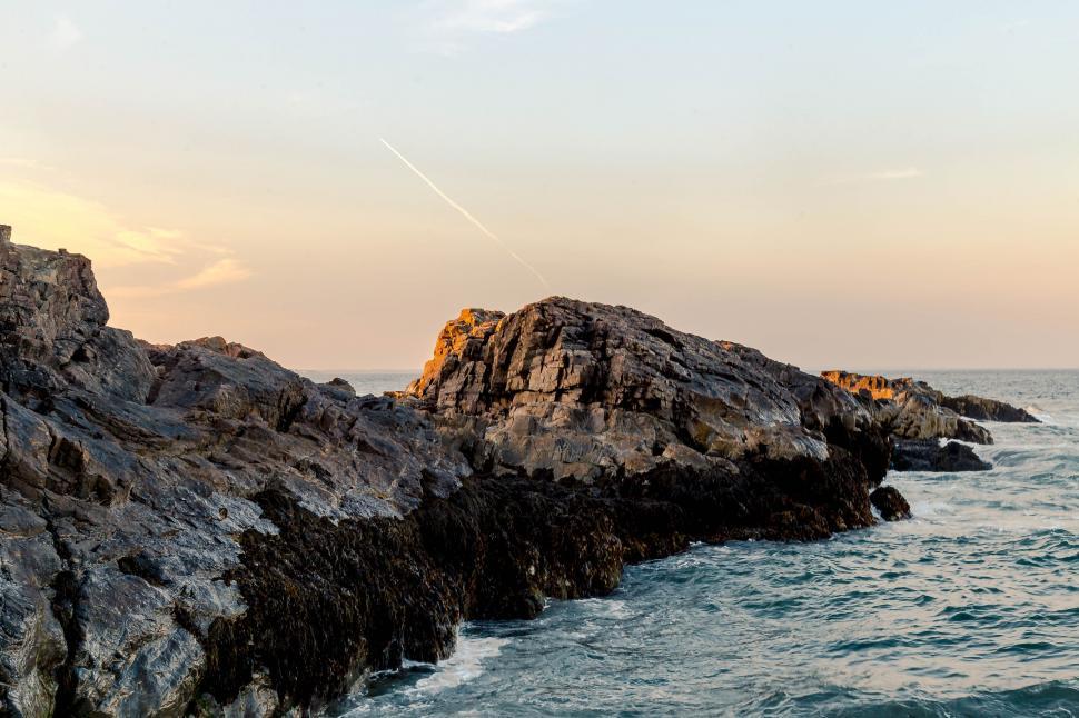 Free Image of Man Standing on Top of Rock Next to Ocean 