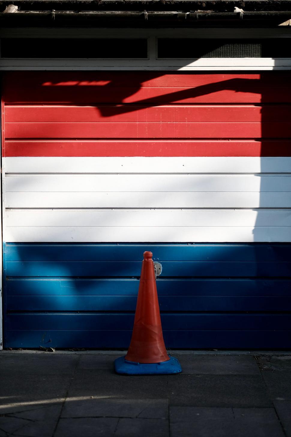 Free Image of Red White and Blue Fire Hydrant Next to a Garage 