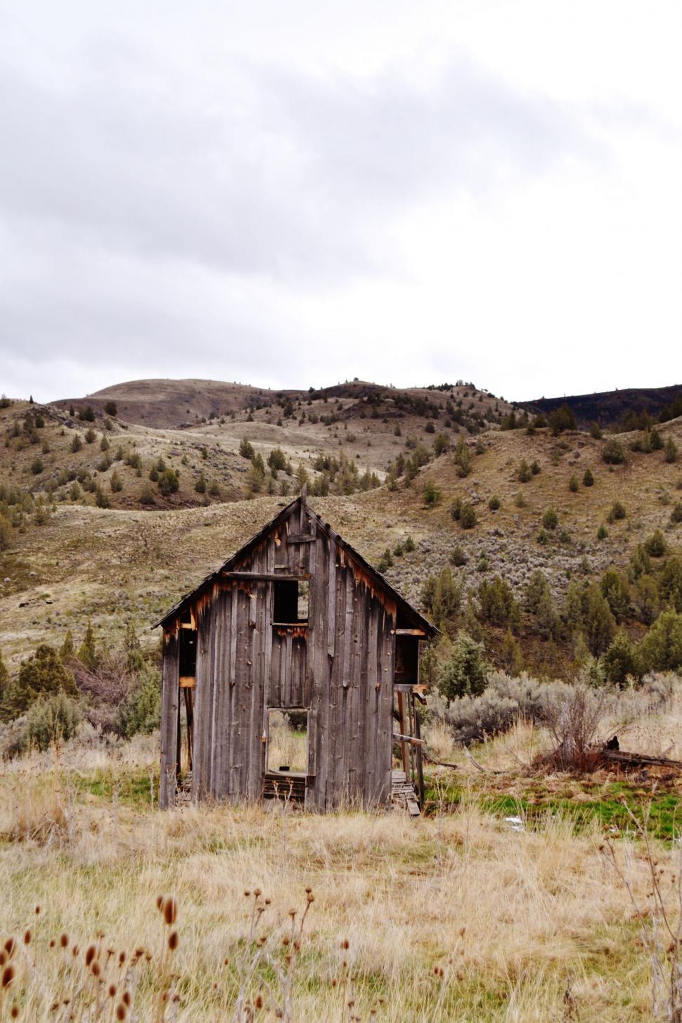 Free Image of Old Wooden Building in Field With Mountain Background 
