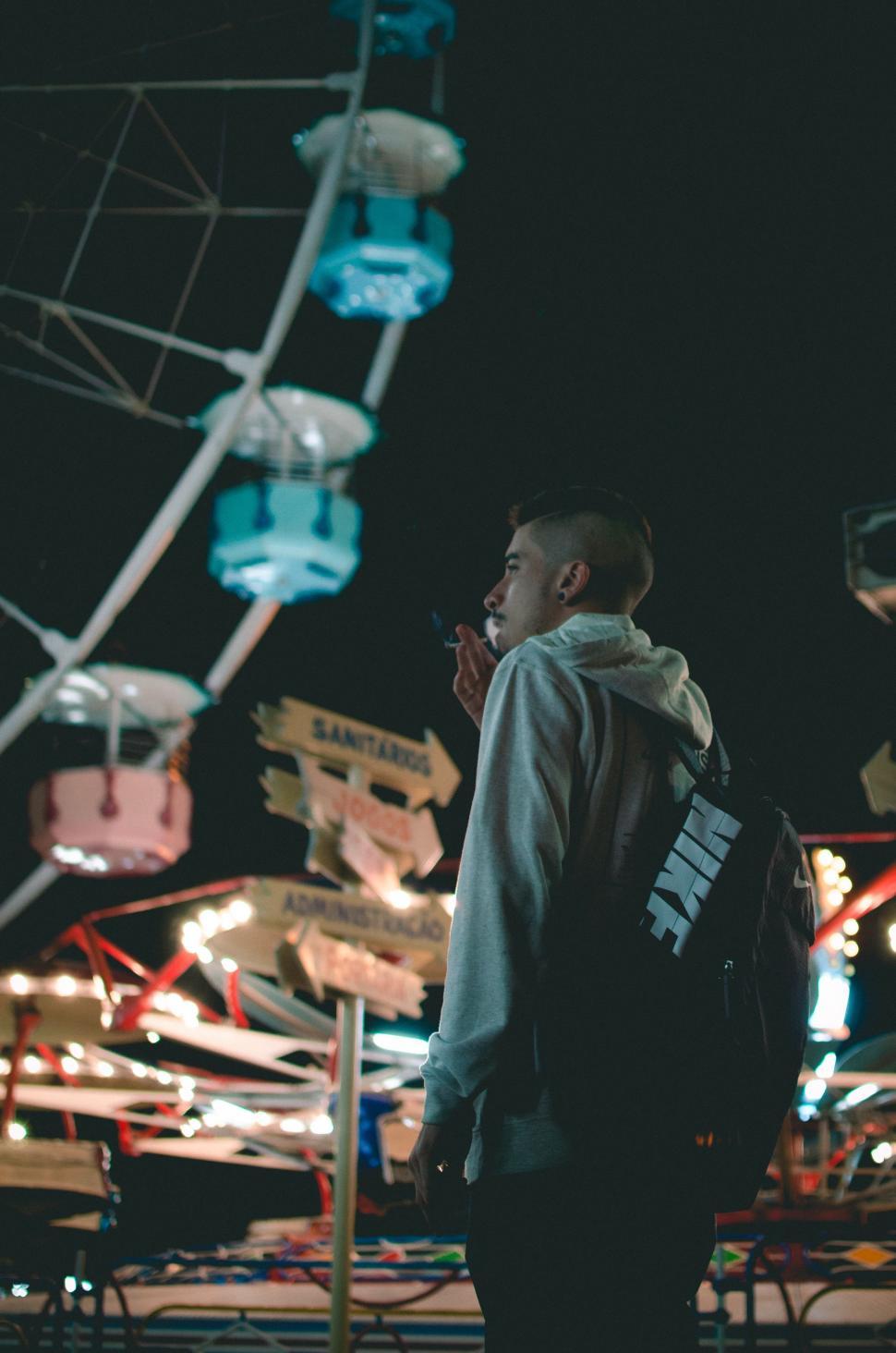 Free Image of Man Standing in Front of Ferris Wheel at Night 