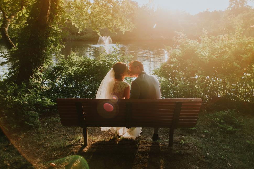 Free Image of Bride and Groom Kissing on Park Bench 