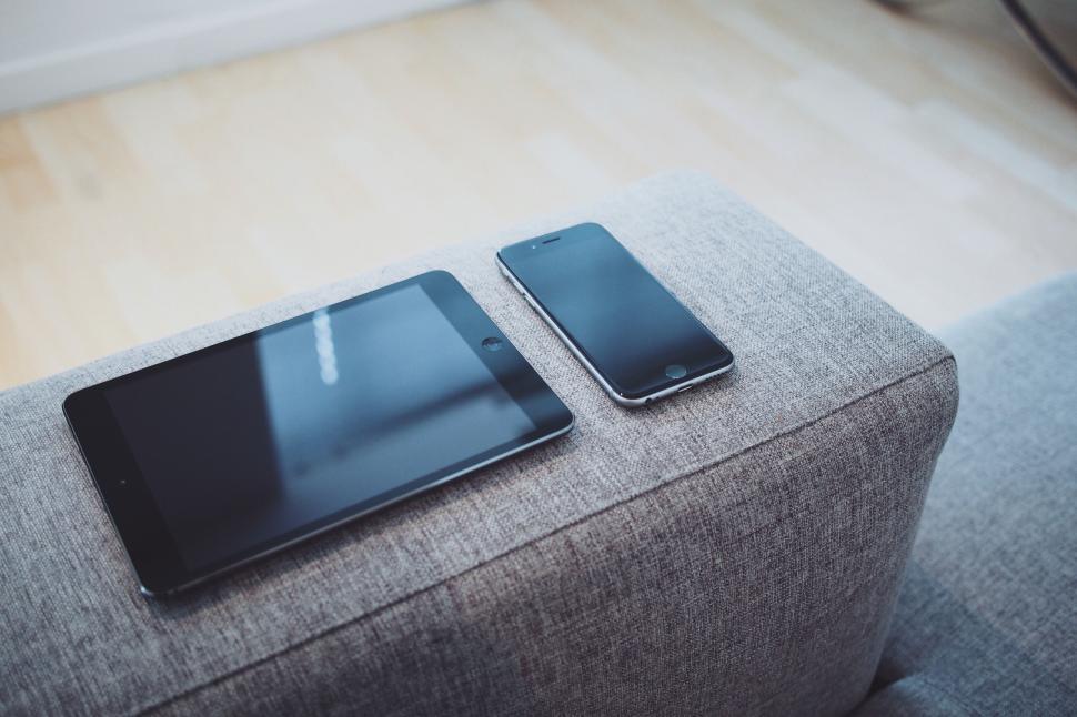 Free Image of Two Cell Phones Resting on a Couch 