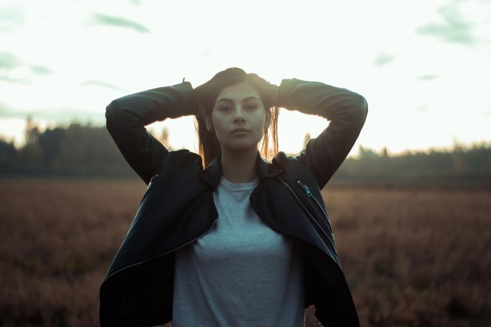 Free Image of Woman Standing in Field With Hands on Head 