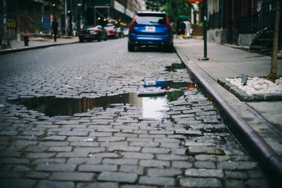 Free Image of Blue Car Driving Along Street Next to Puddle 