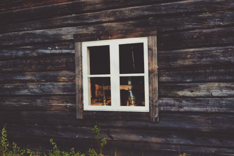 Free Image of Dog Observing Surroundings From Window of Log Cabin 