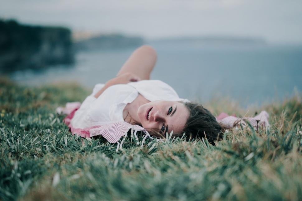 Free Image of Woman in White Dress Laying in Grass 