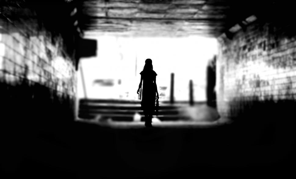 Free Image of Woman Walking Down Dark Tunnel 