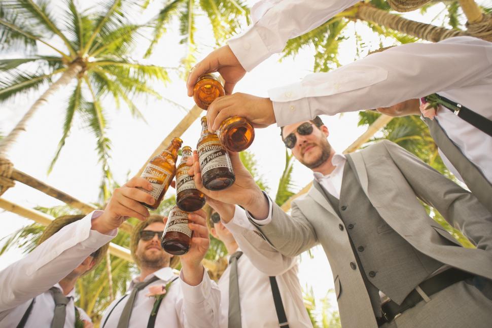 Free Image of Men Standing Around Each Other Holding Bottles of Beer 
