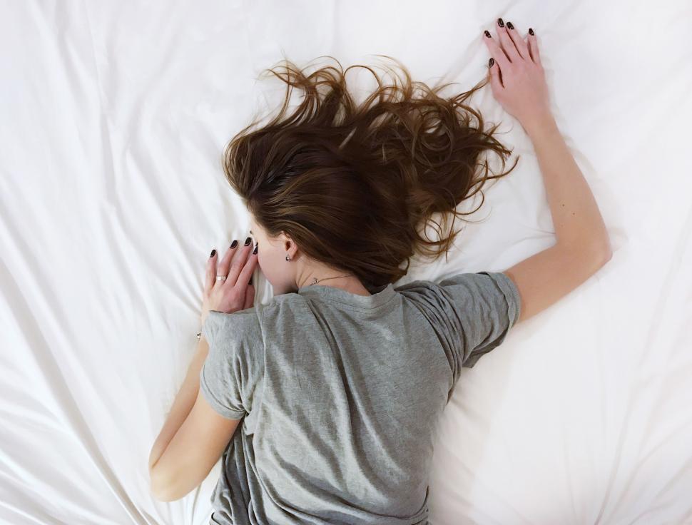 Free Image of Woman Laying in Bed With Hair Blowing in Wind 