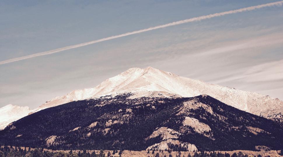 Free Image of Snow Covered Mountain With Contrails in the Sky 