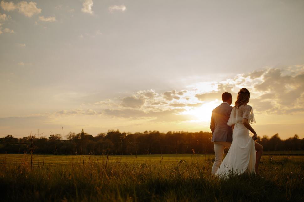 Free Image of Bride and Groom Standing in Field at Sunset 